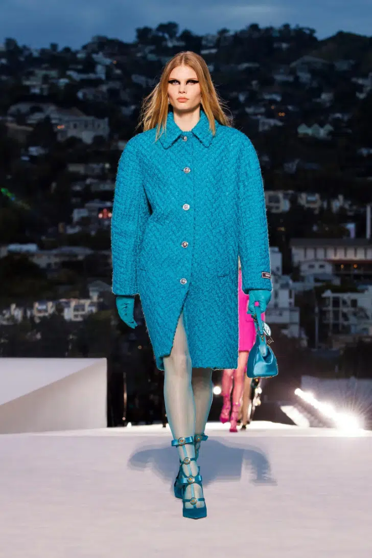 Модель в голубом стеганном пальто оверсайз по колено от Versace