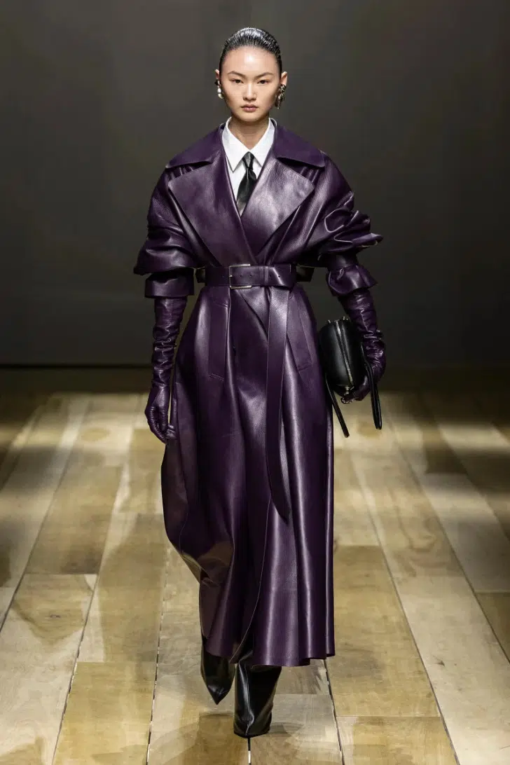 Модель в кожаном пальто с поясом на талии фиолетового цвета от Alexander McQueen