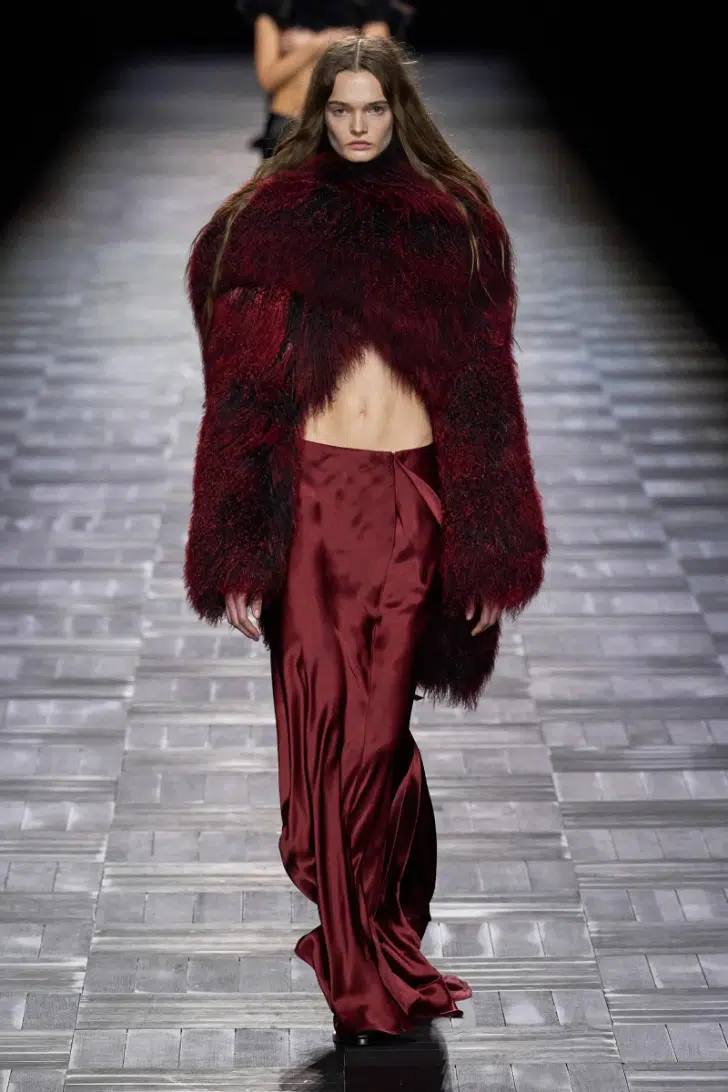 Модель в укороченном меховом пальто бордового цвета от Ann Demeulemeester