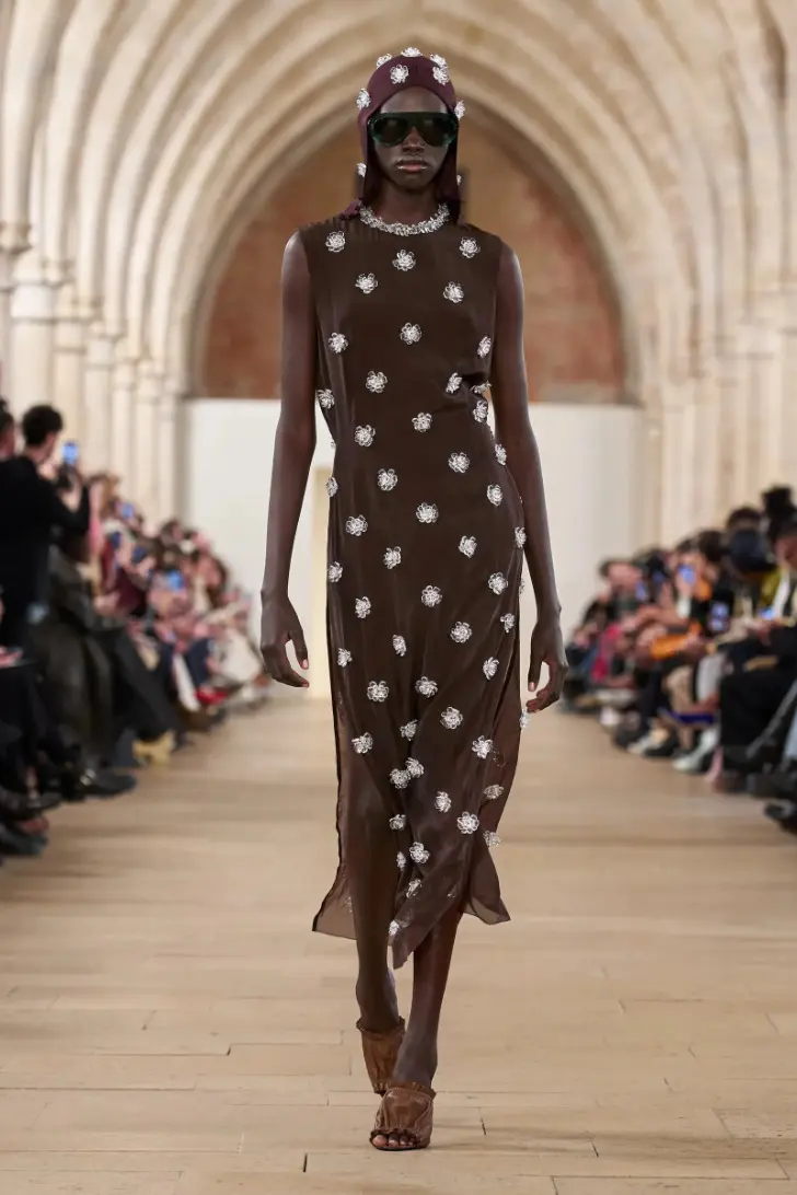 Модель в узком коричневом платье миди без рукавов и босоножках