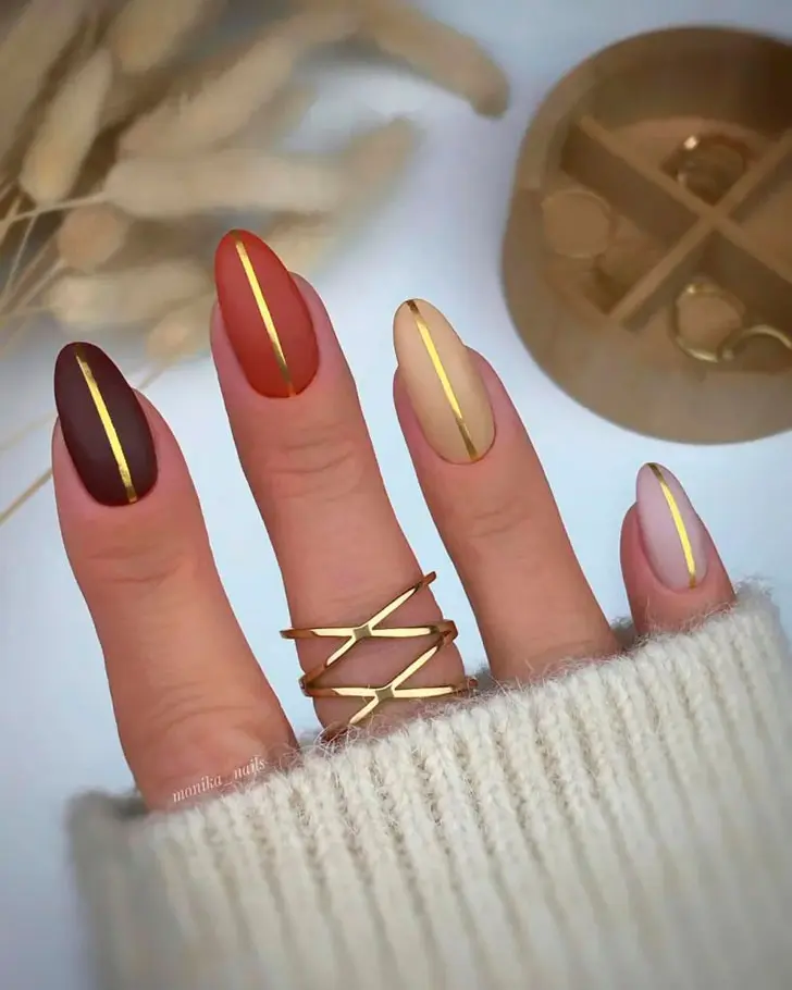 Осенний градиент с золотыми линиями на овальных ногтях