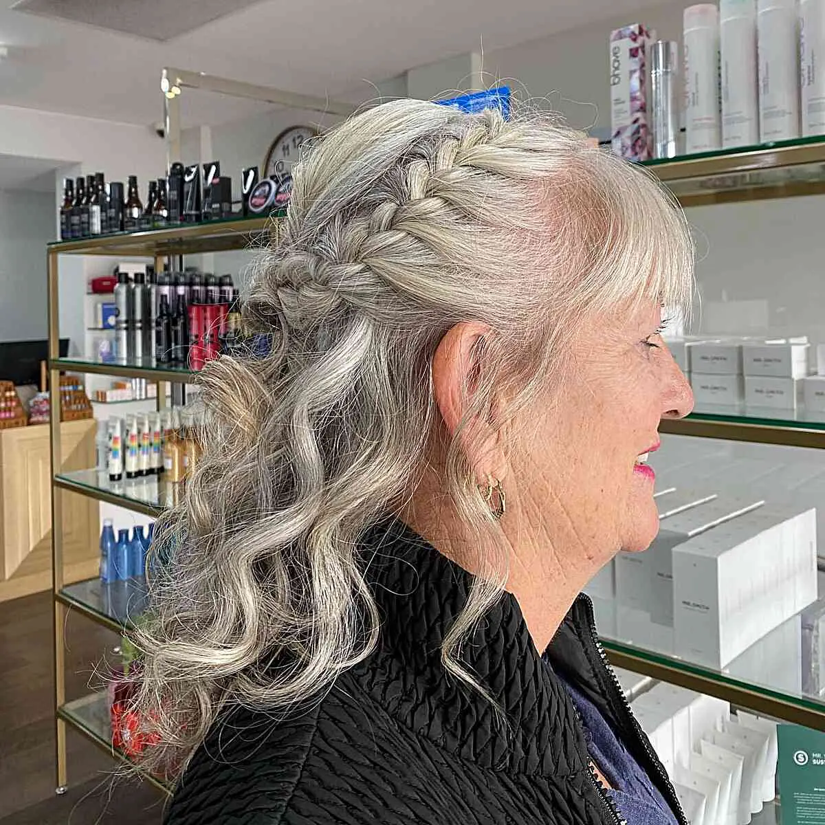 Женщина с легкими локонами и боковой французской косой на седых тонких волосах
