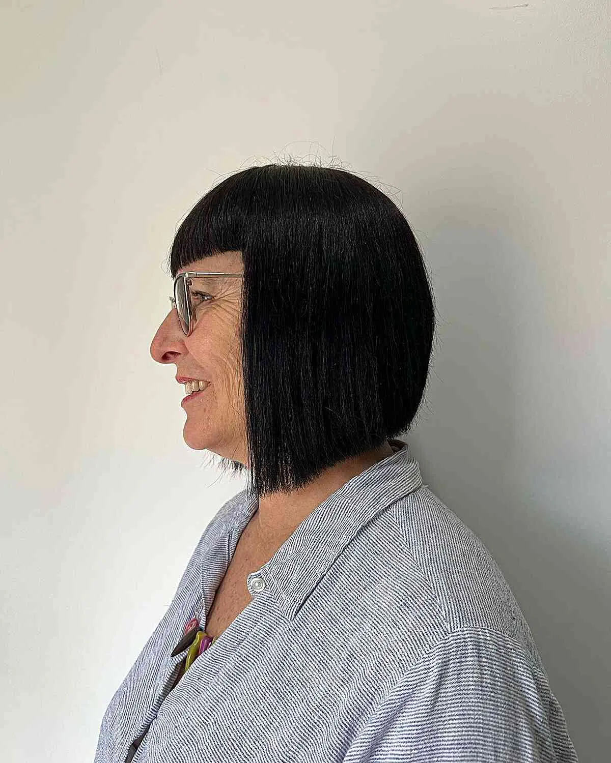 Женщина со стрижкой блант боб с прямой челкой на темных гладких волосах