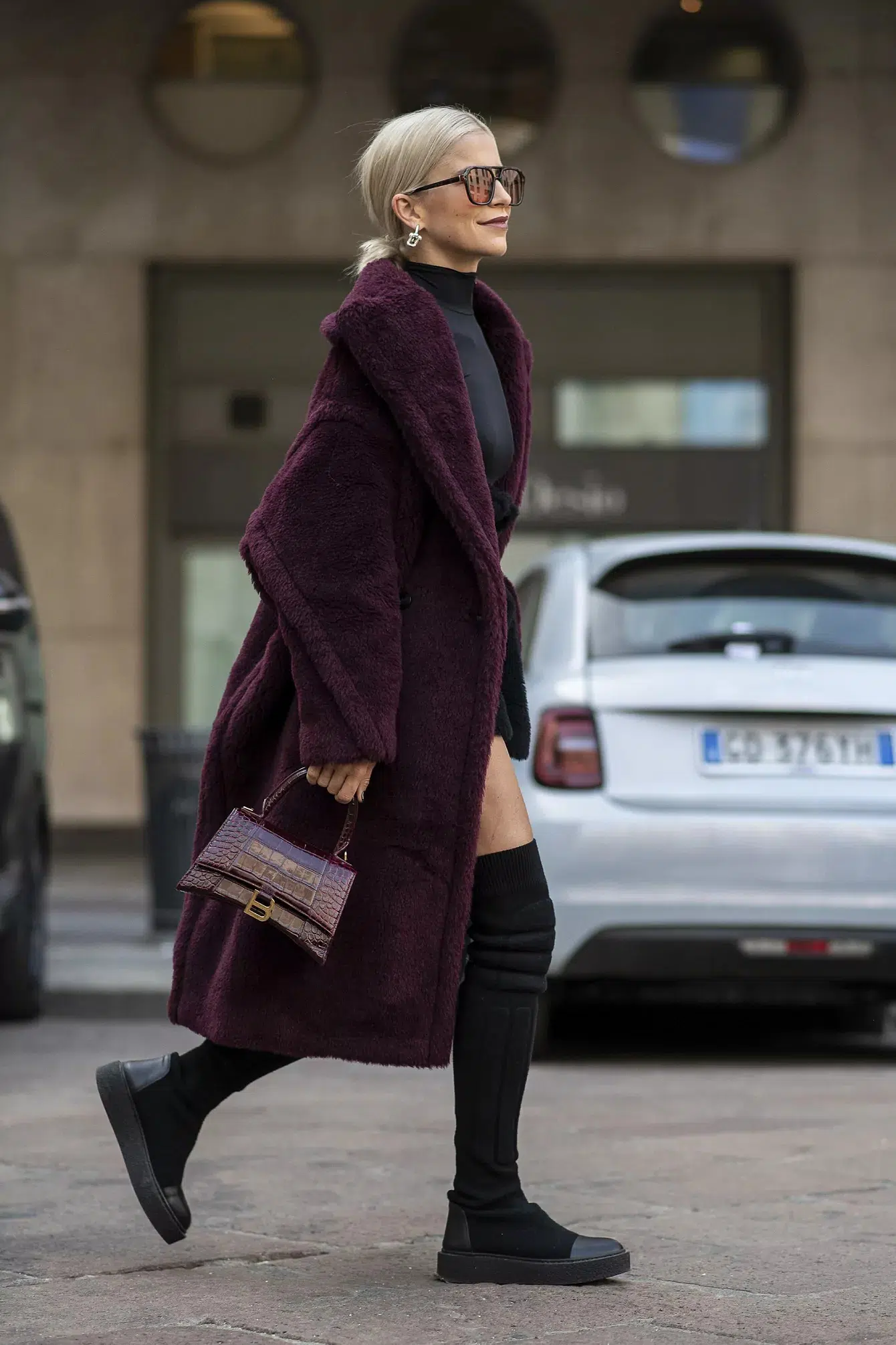 Женщина в бордовом плюшевом пальто и черных ботинках