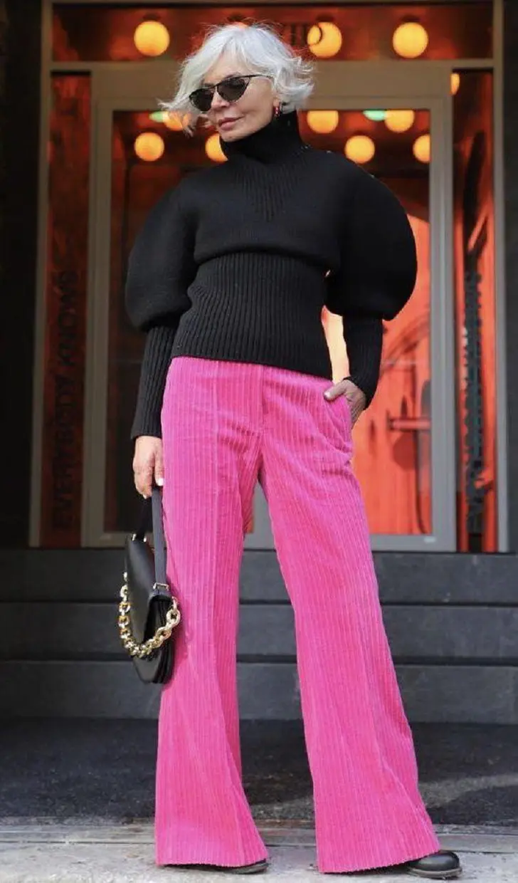 Женщина в черном свитере и розовых вельветовых брюках