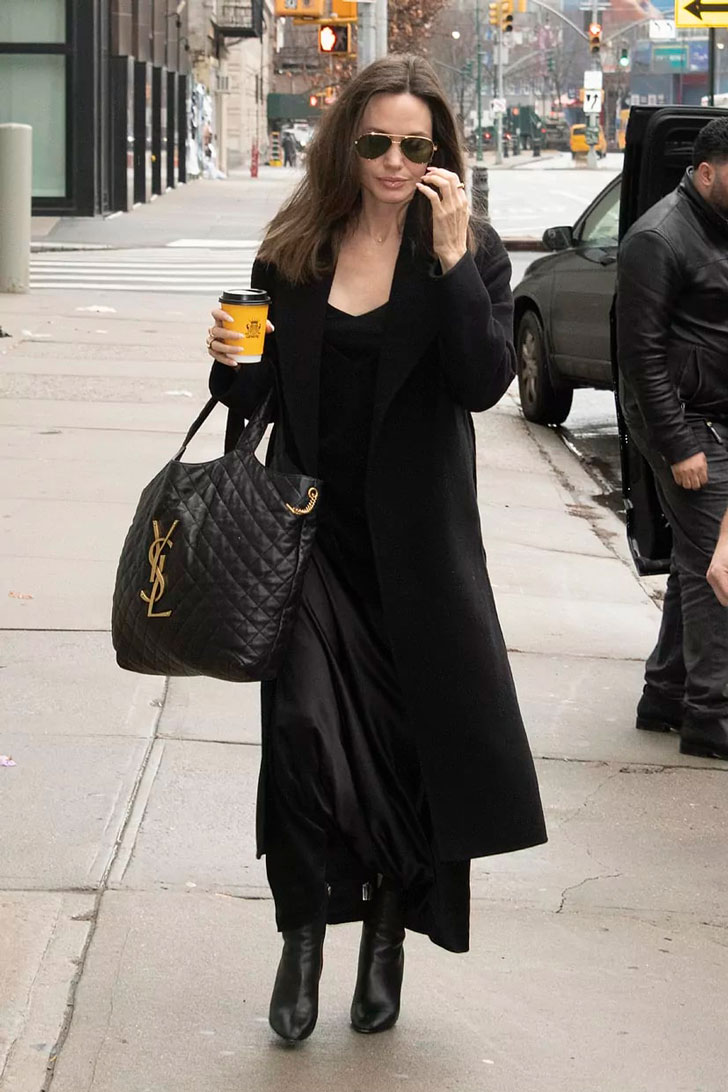 Анджелина Джоли в черном классическом пальто, юбке миди и объемной черной сумке