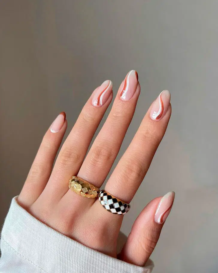 Бело-коричневые завитки на натуральных овальных ногтях средней длины