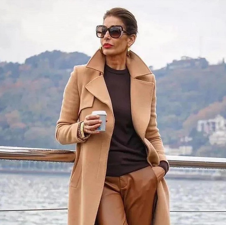 Женщина в бежевом пальто с кожаными брюками и коричневым джемпером