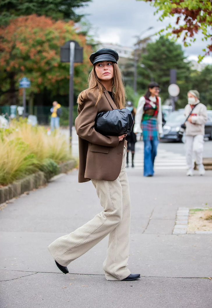 Девушка в бежевых брюках из вельвета, модном пиджаке и французской кепи