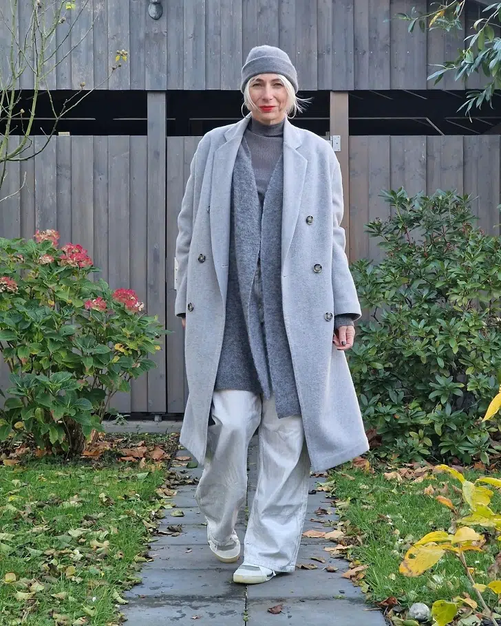 Женщина в серых джинсах, пальто и кедах