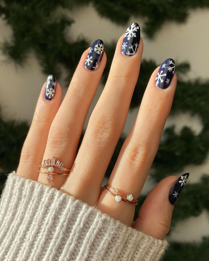 Темно-синий маникюр с белыми снежинками на овальных ногтях средней длины