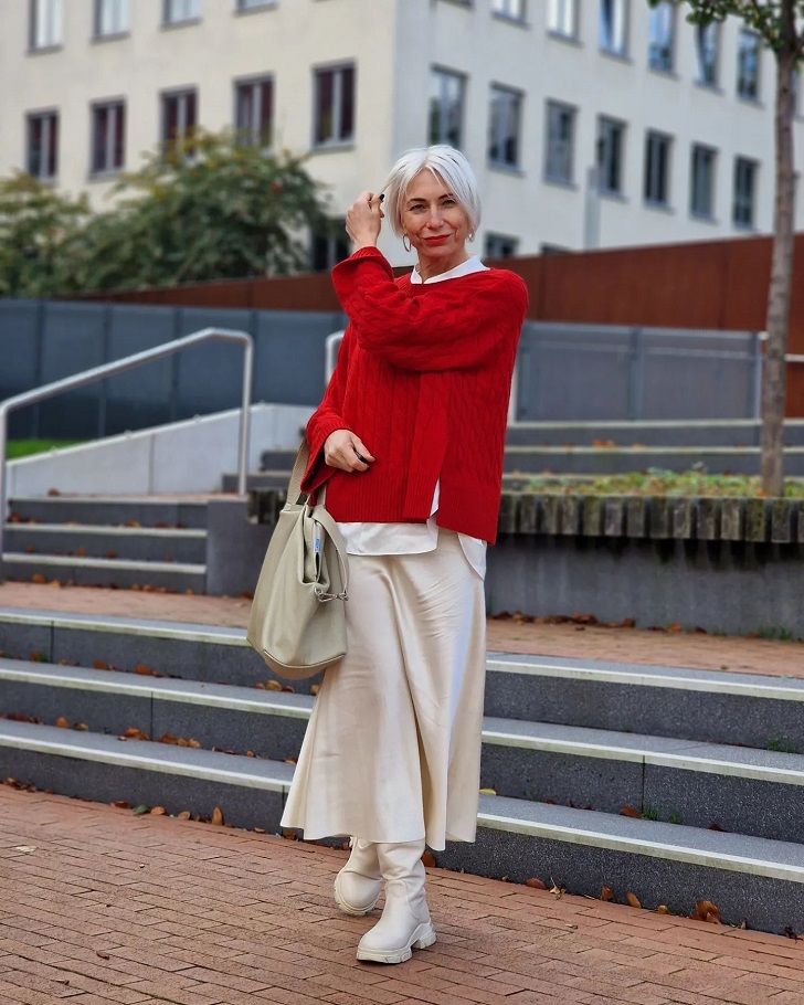Женщина в красном свитере, молочной юбке из атласа и такого же оттенка сапогах