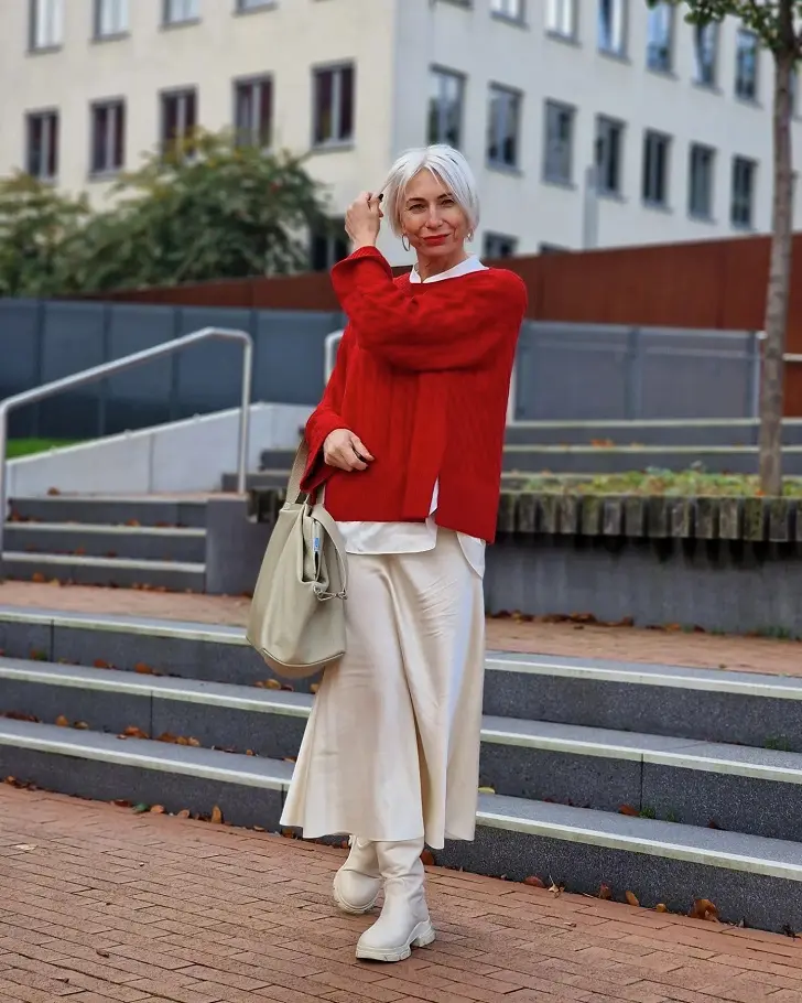 Женщина в красном свитере, молочной юбке из атласа и такого же оттенка сапогах