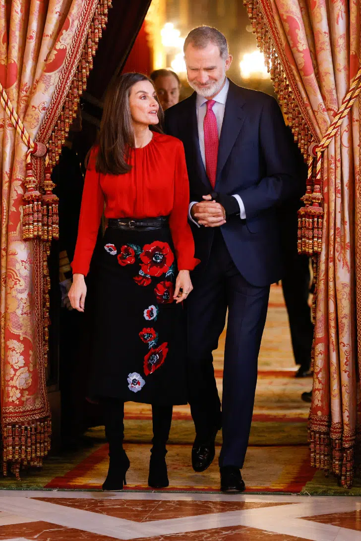 Королева Летиция в юбке с красными цветами и черных сапогах из матовой кожи