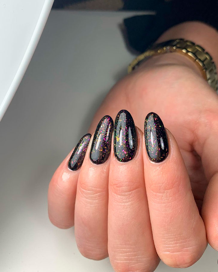 Праздничный черный маникюр с блестками на овальных ногтях