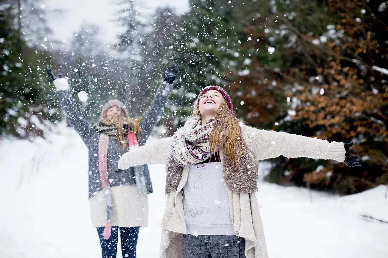 Счастливые девушки в свитерах посреди снега