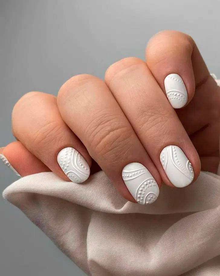 Белый маникюр с рельефными узорами на коротких ногтях
