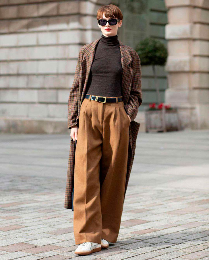 Девушка в коричневых брюках палаццо с ремнем и коричневом длинном пальто