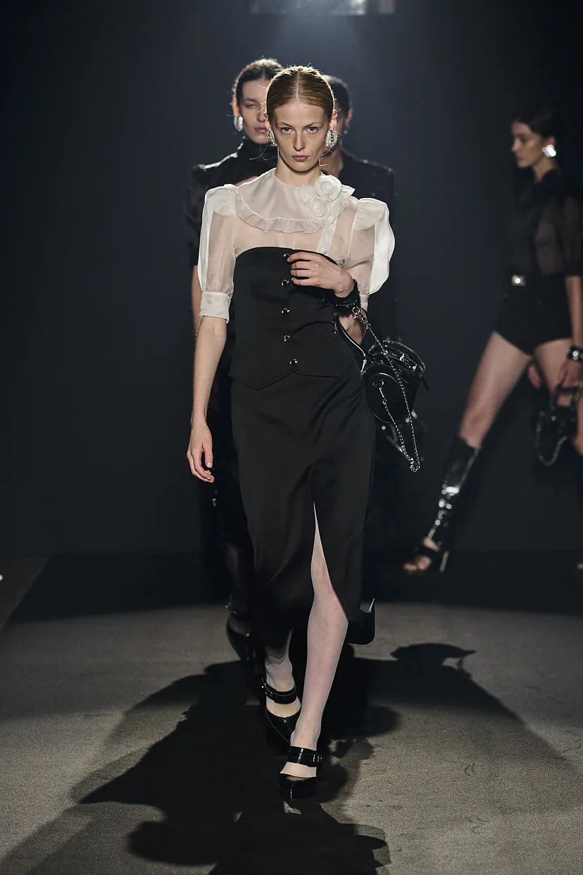 Модель в черном облегающем платье с блузой сверху от Alessandra Rich