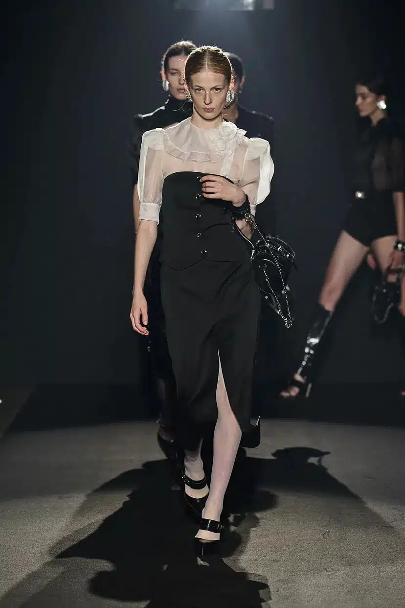 Модель в черном облегающем платье с блузой сверху от Alessandra Rich
