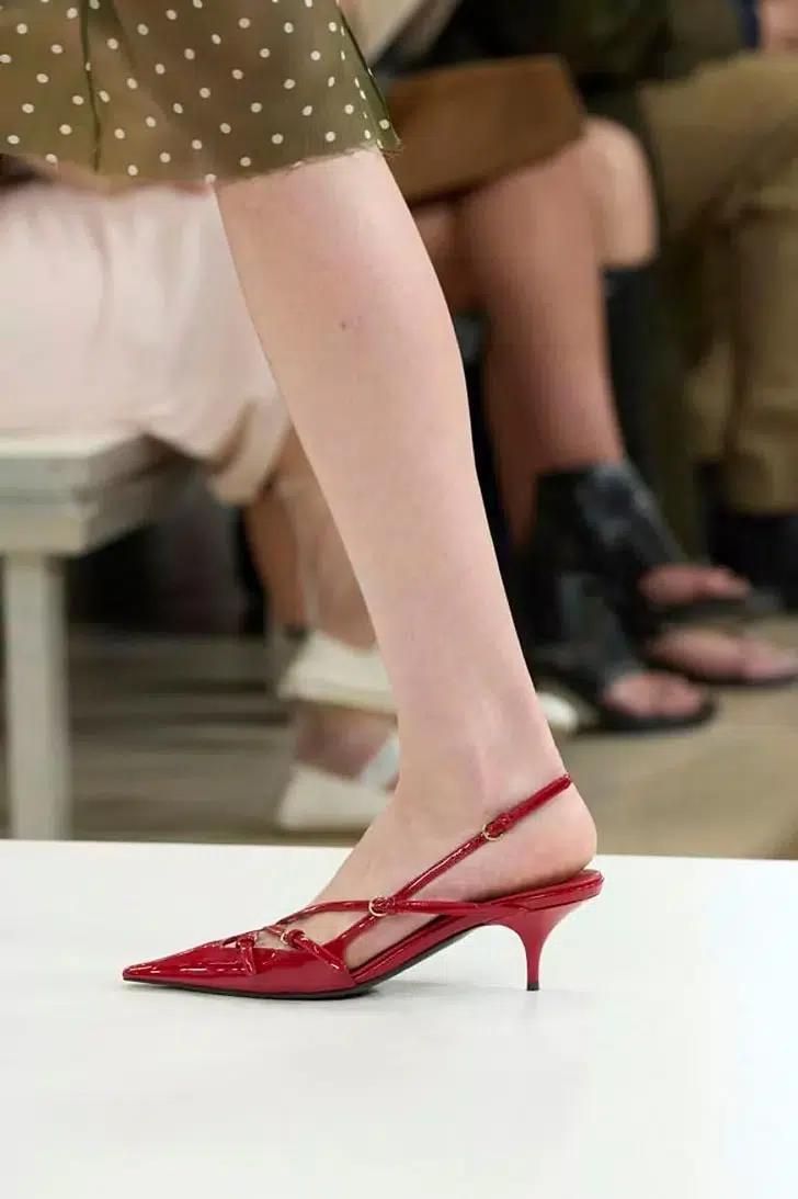 Модель в красных туфлях с ремешком на пятке и низким каблуком от Miu Miu