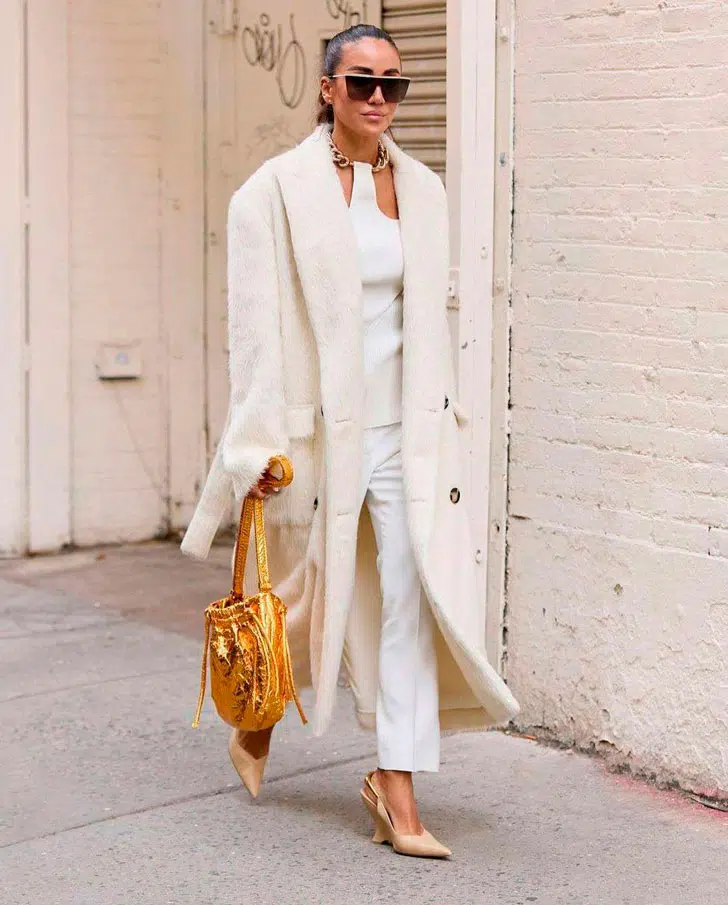 Женщина в мягком пальто молочного цвета и белых брюках
