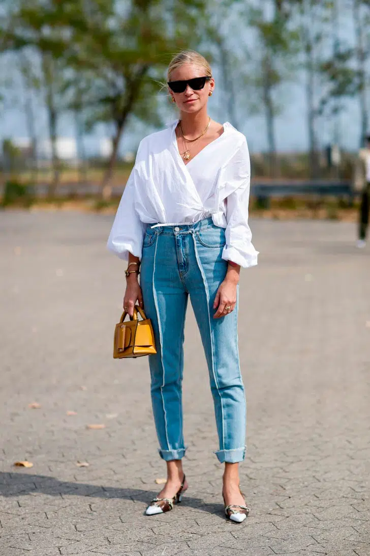 Девушка в голубых джинсах до щиколотки, белой блузе и туфлях