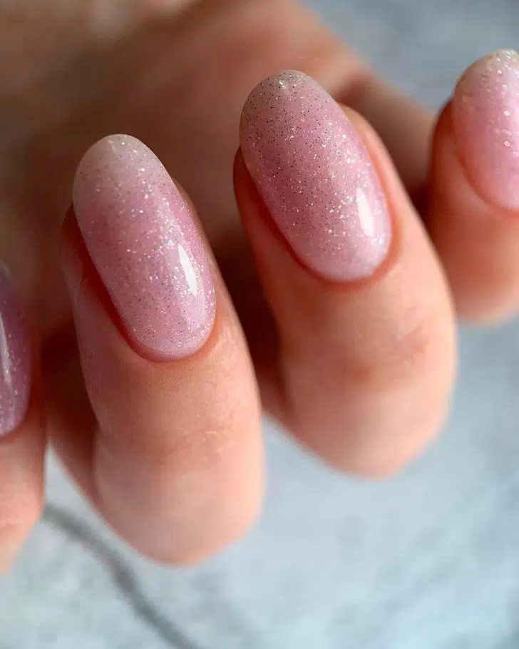 Розовый маникюр с мелкими блестками на овальных ногтях средней длины