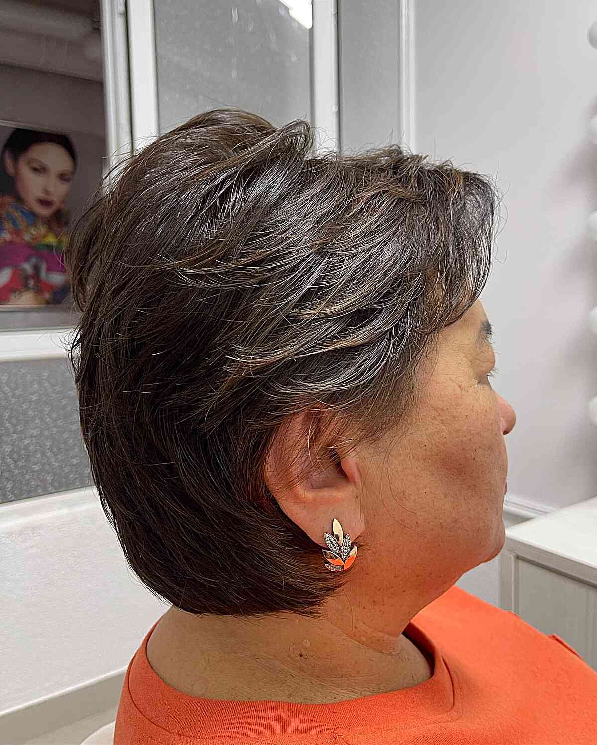 Женщина с многослойной стрижкой пикси с боковой челкой на темных волосах