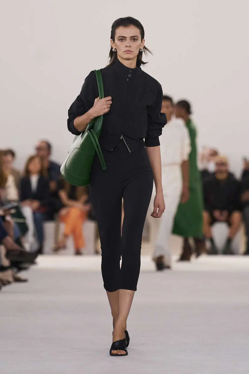 Модель в черных брюках капри и черной спортивной кофте от Ferragamo
