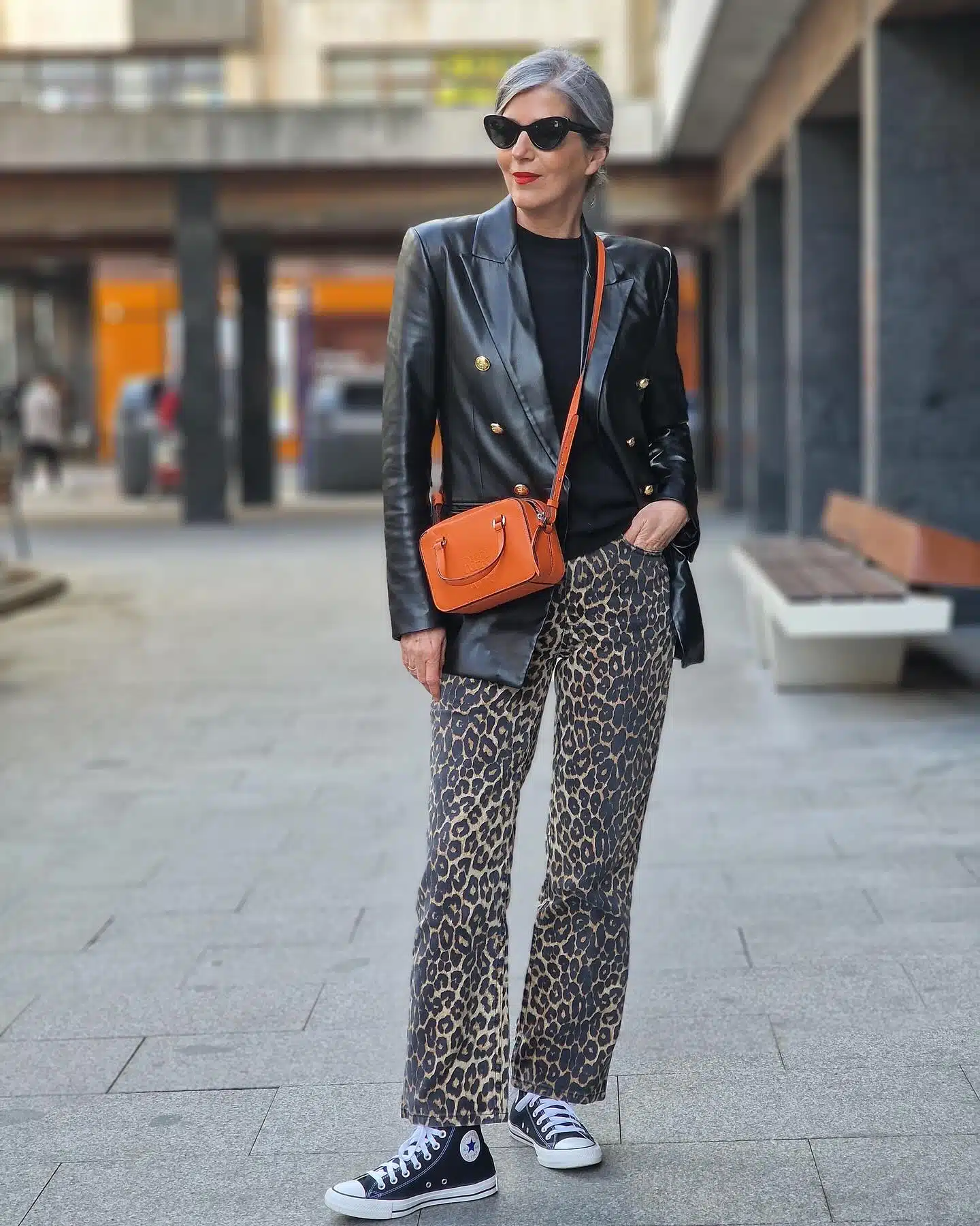 Брюки с леопардовым принтом с кедами черным джемпером и кожаным пиджаком