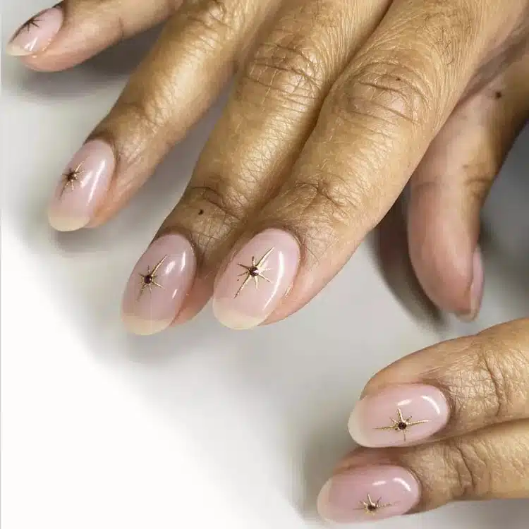 Натуральный маникюр с золотыми звездами на овальных ногтях средней длины