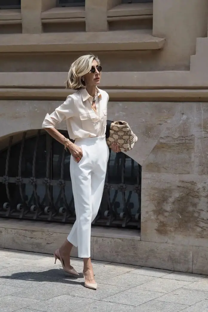 Женщина за 60 в элегантных белых брюках, рубашке и туфлях